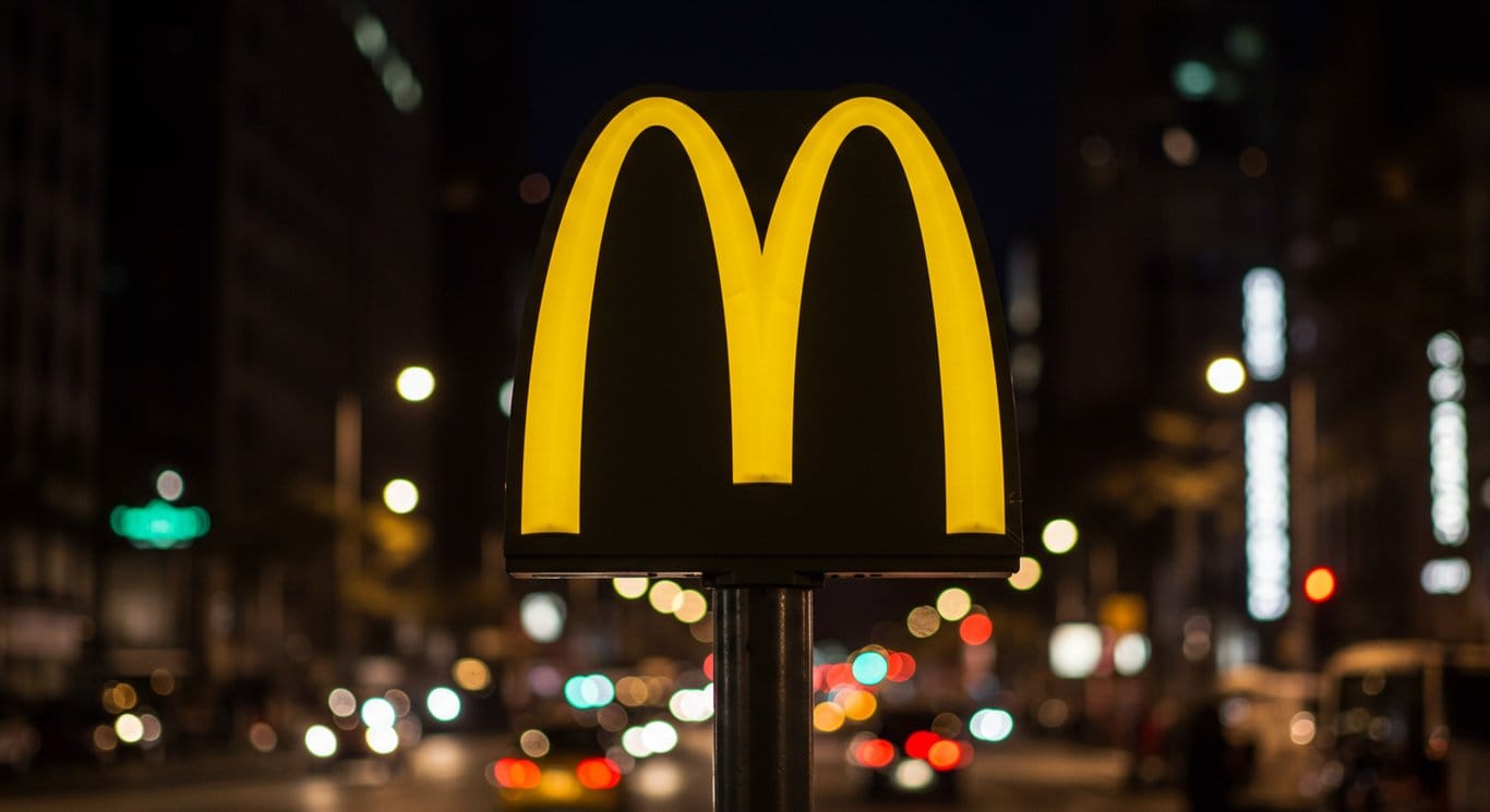 McDonald's Golden Arches logo against a blurred city backdrop.